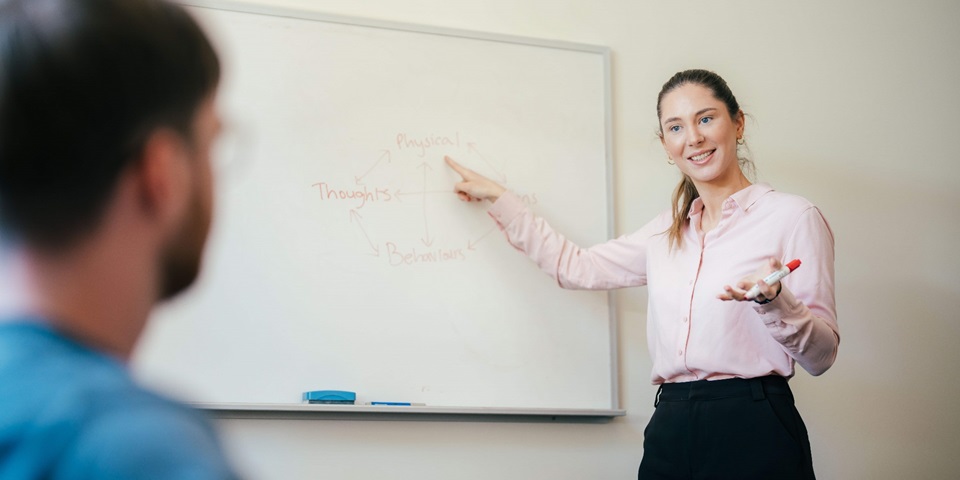 Female psychologist pointing at whiteboard to teach student