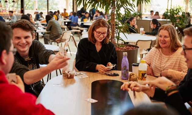 Staff and students playing cards in Student Hub