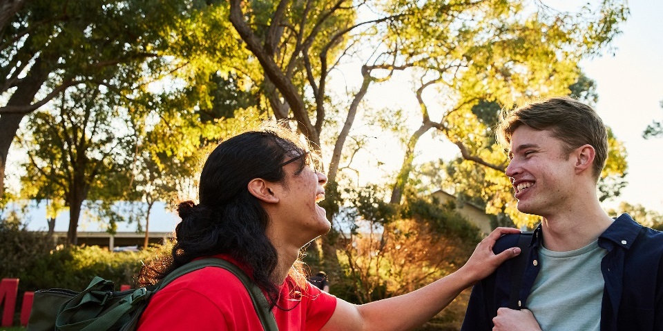 Two students laughing together on Bush Court